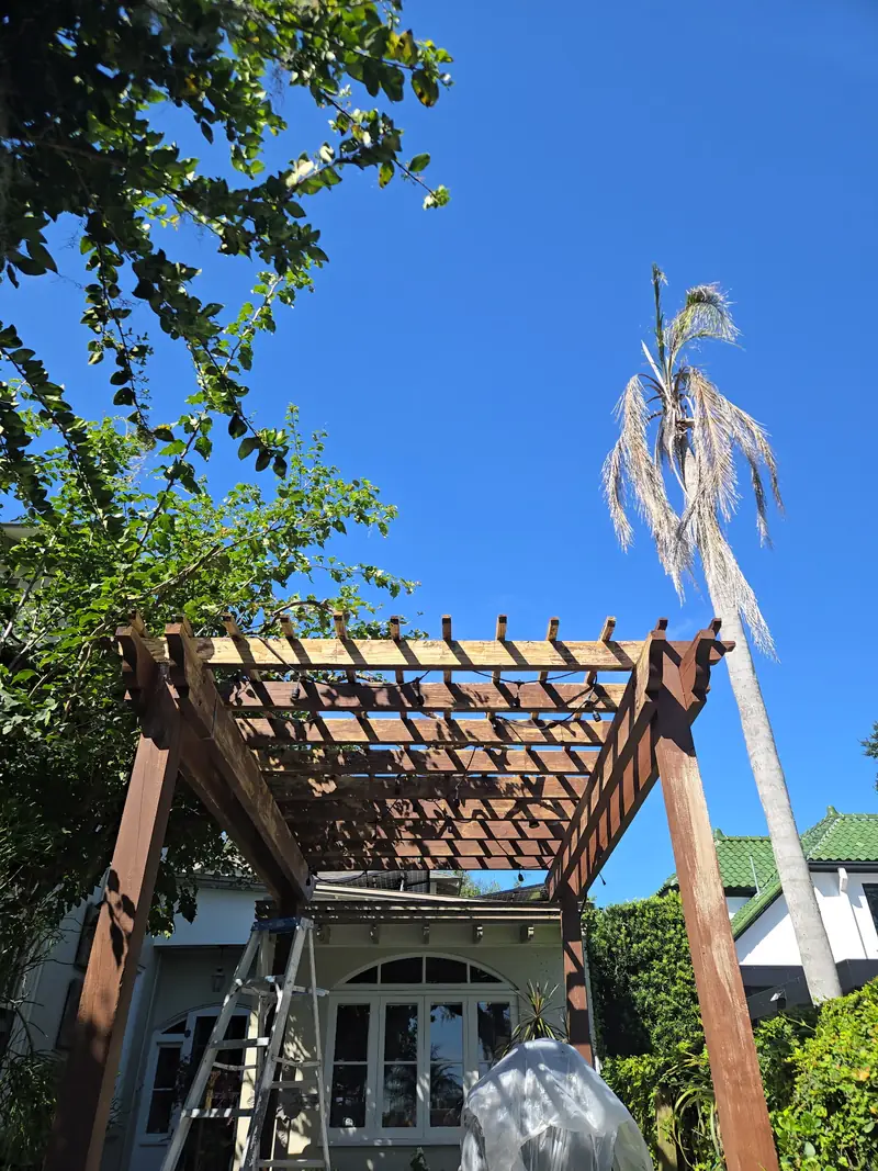 Sun-weathered pergola rafters before refinishing