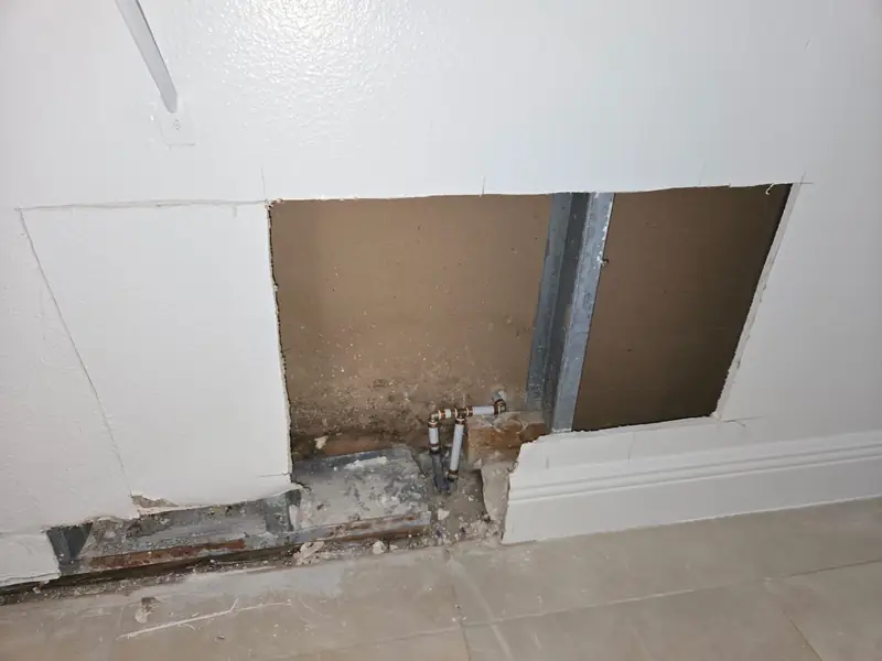 Water-damaged drywall opened at the base to trace the leak